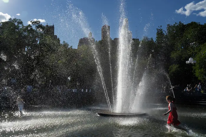 A photo of kids running through sprinklers in Washington Square Park